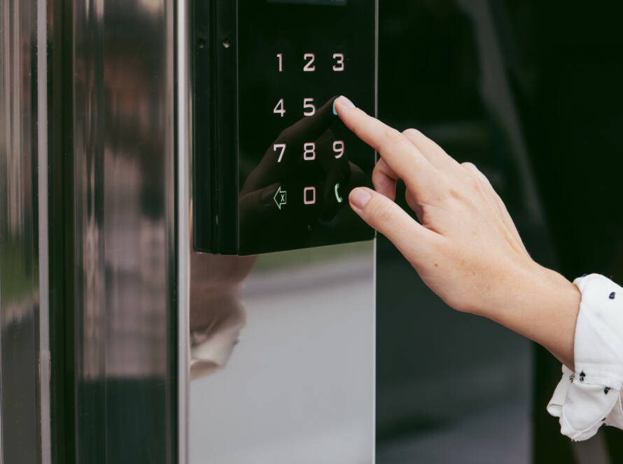 Woman's hand using an intercom at entrance to building. Using an electronic lock.